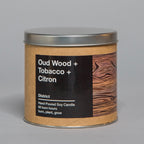 Hand poured soy candle with oud wood, tobacco, and citron scent in a tin container with wood grain design label