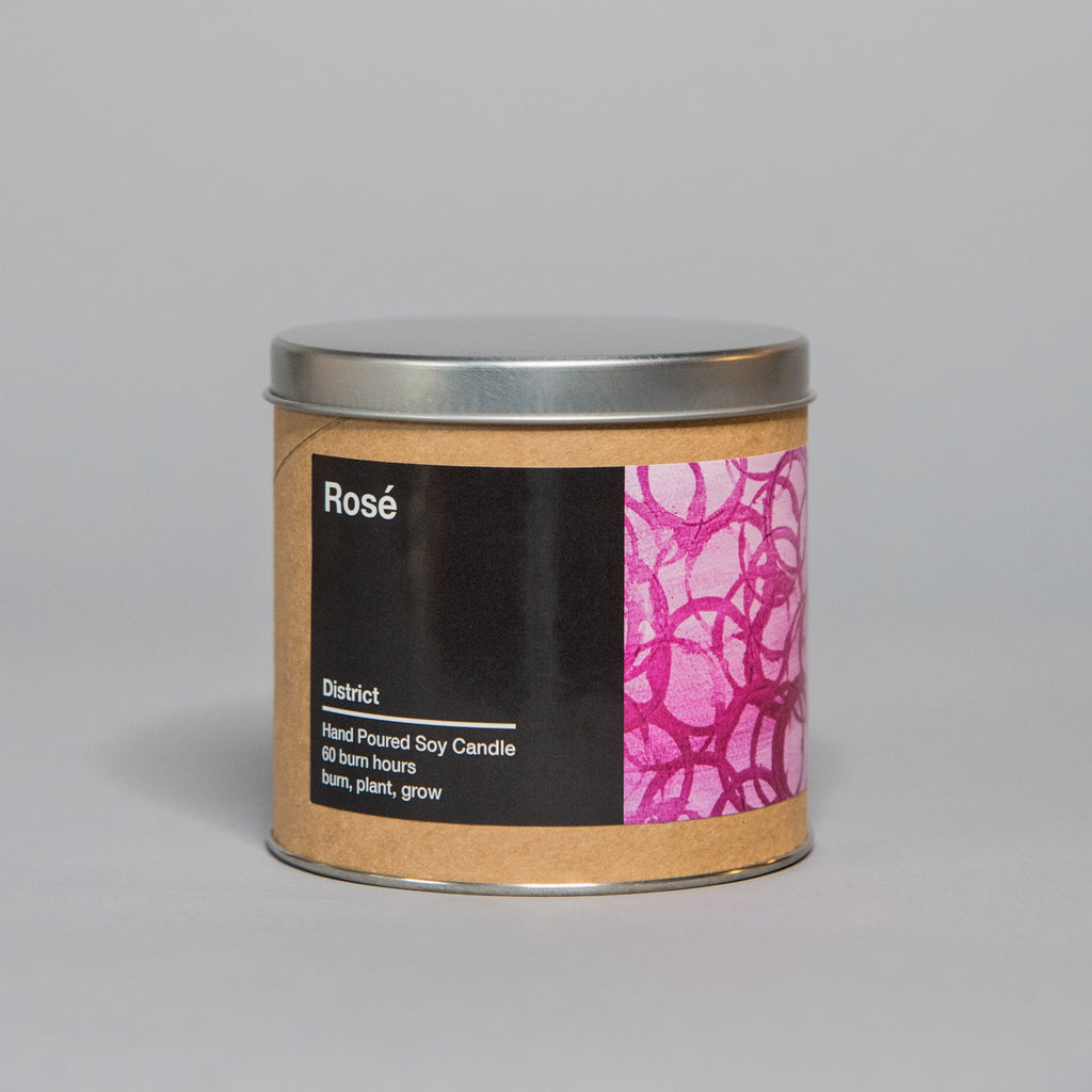 Small hand-poured soy candle in a metal tin with a brown label featuring pink abstract artwork and black text