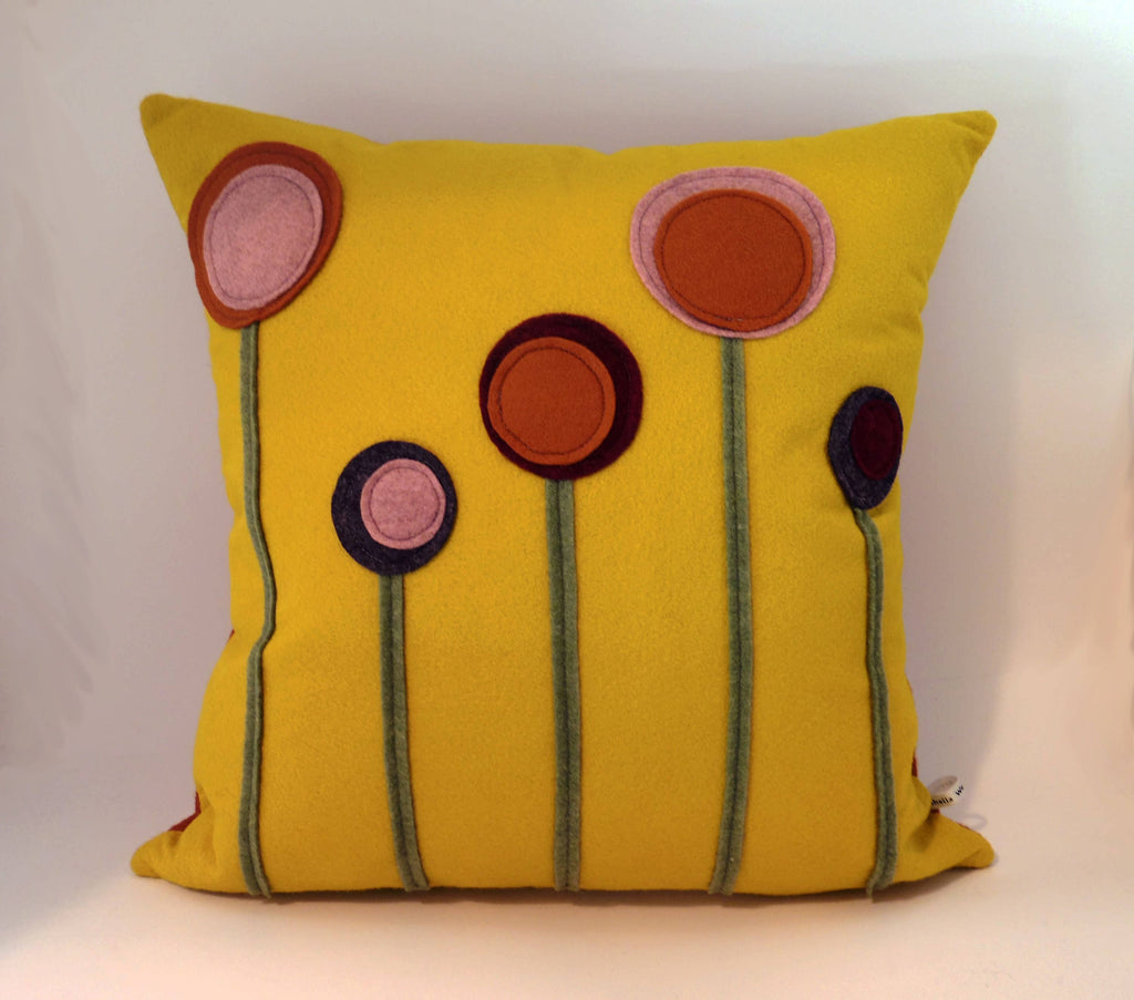 Yellow wool felt pillow with colorful circular flower designs and green stems for home decor.