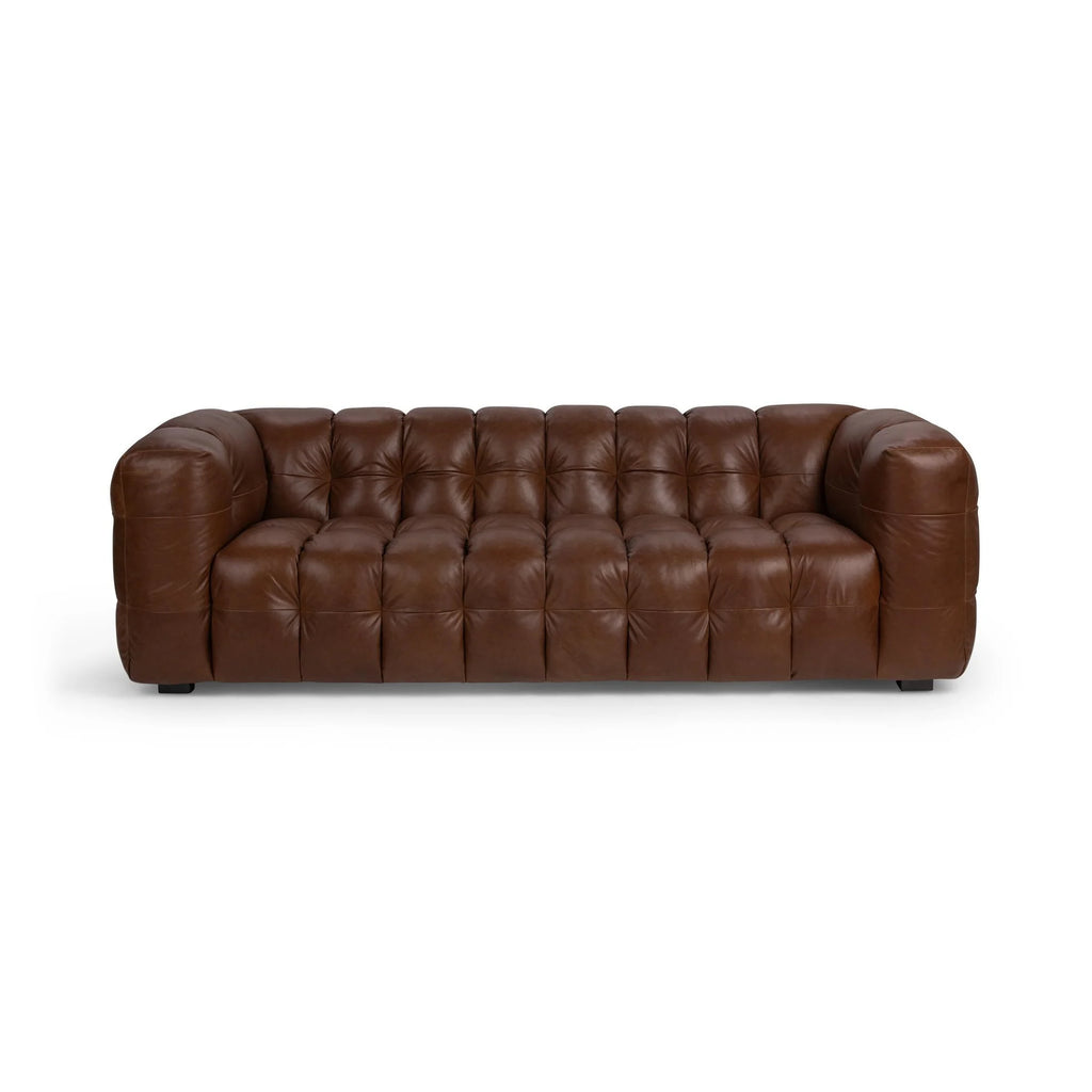 Brown tufted leather sofa with deep cushioning and rounded armrests in a modern design.