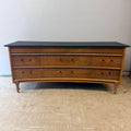 Vintage wooden dresser with curved front and ebony top featuring multiple drawers and simple round knobs.