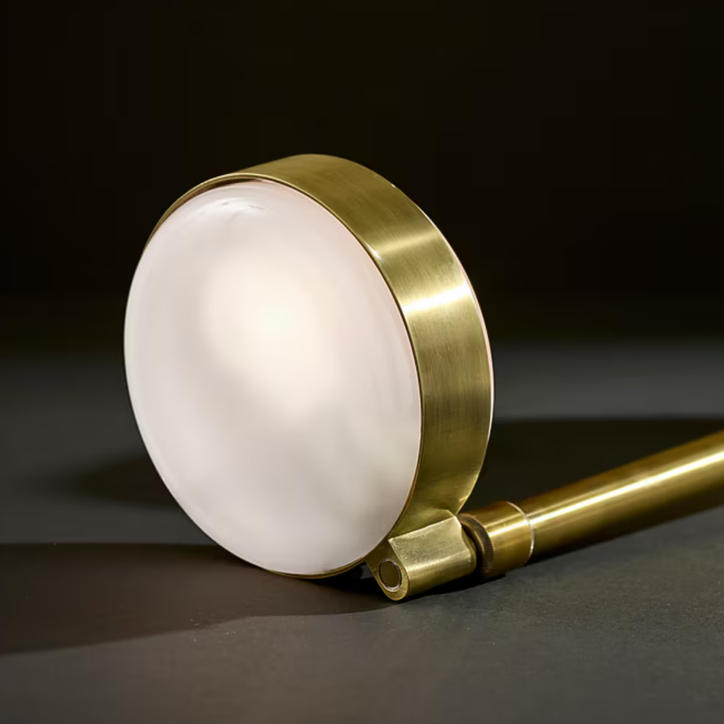 Close-up of a brass table lamp head with a frosted glass diffuser on a dark surface background