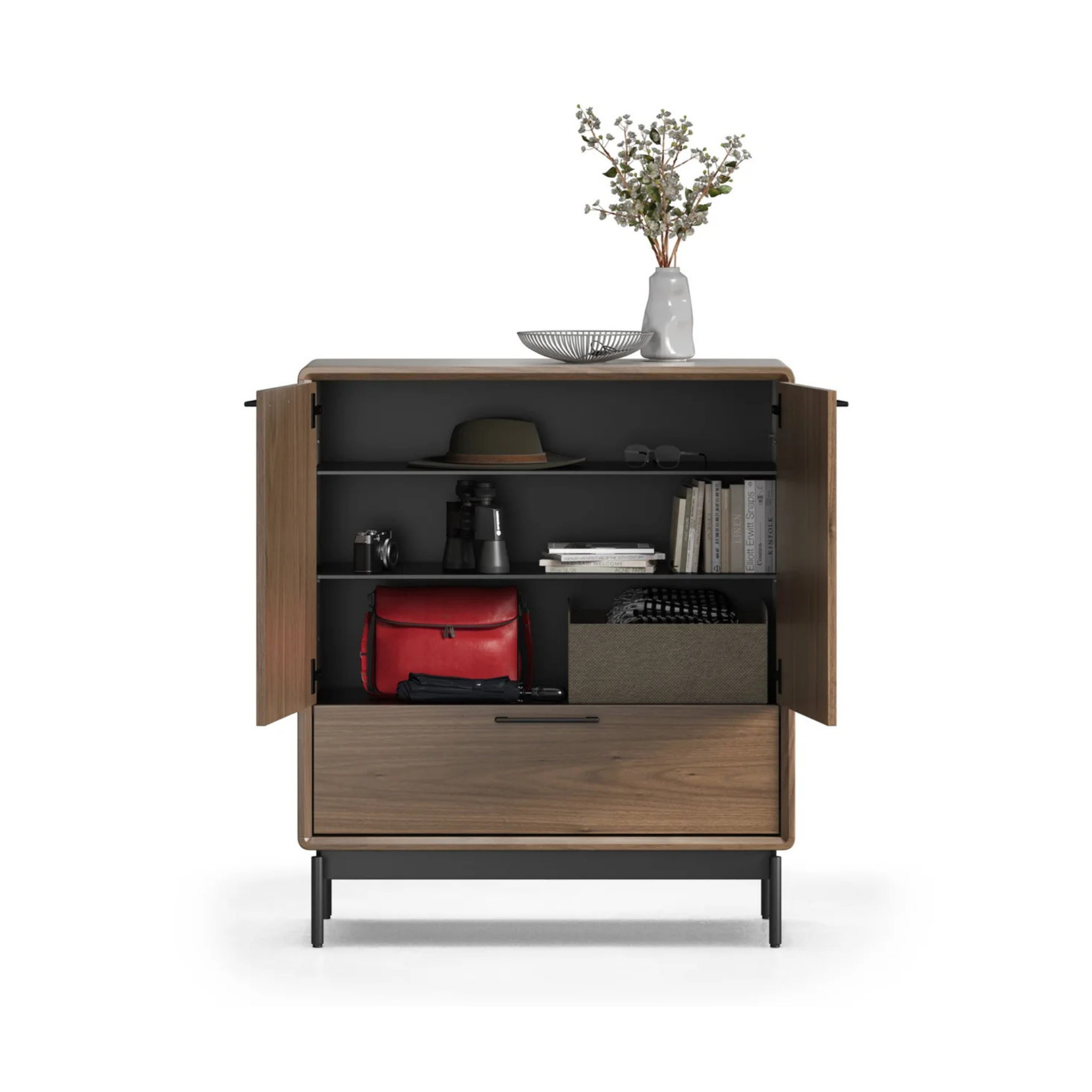 Wooden entry cabinet with open doors displaying organized shelves holding books, binoculars, a hat, and decorative items.