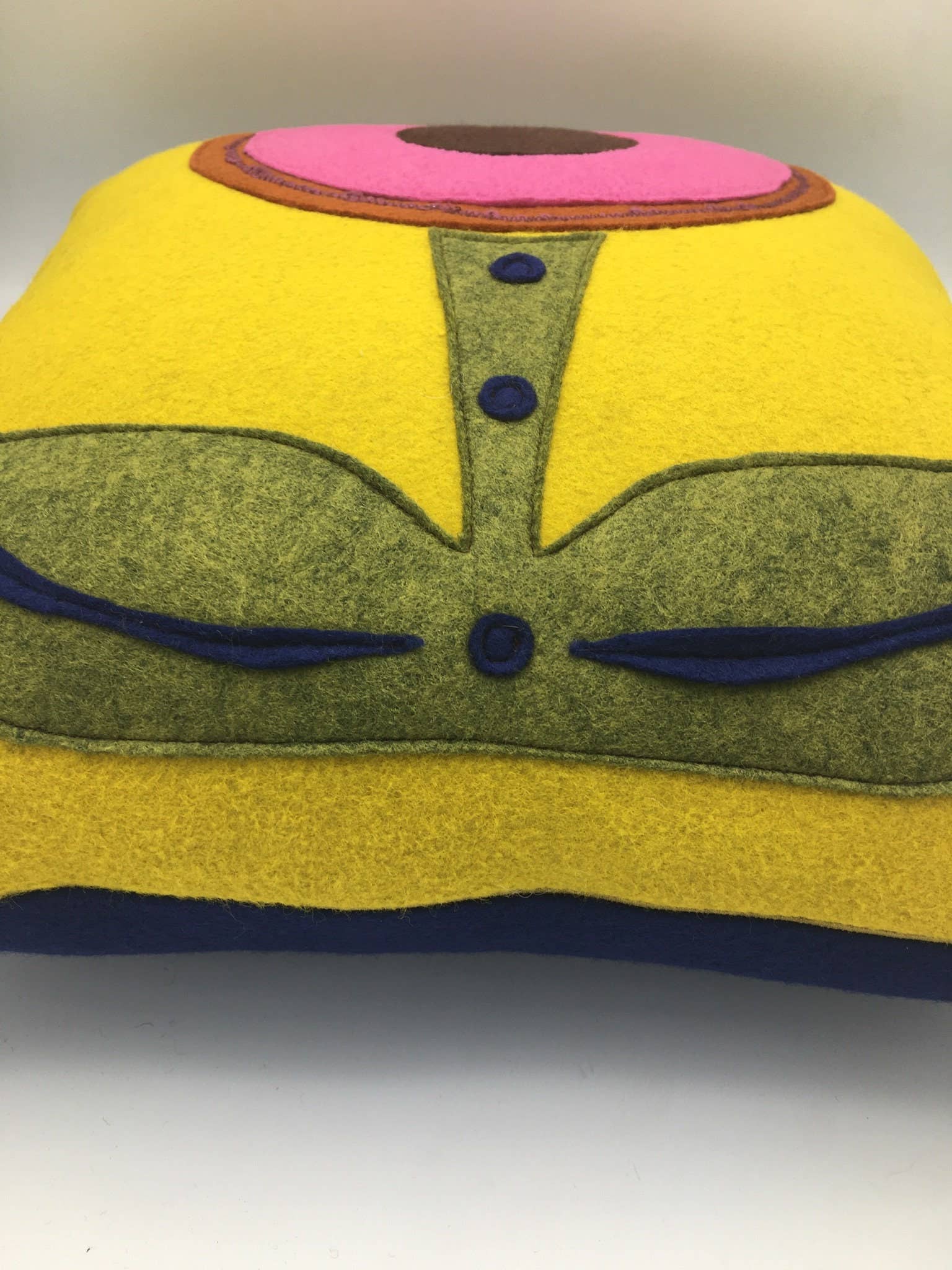 Yellow wool felt pillow with abstract flower design in green, pink, and blue accents for home decor.