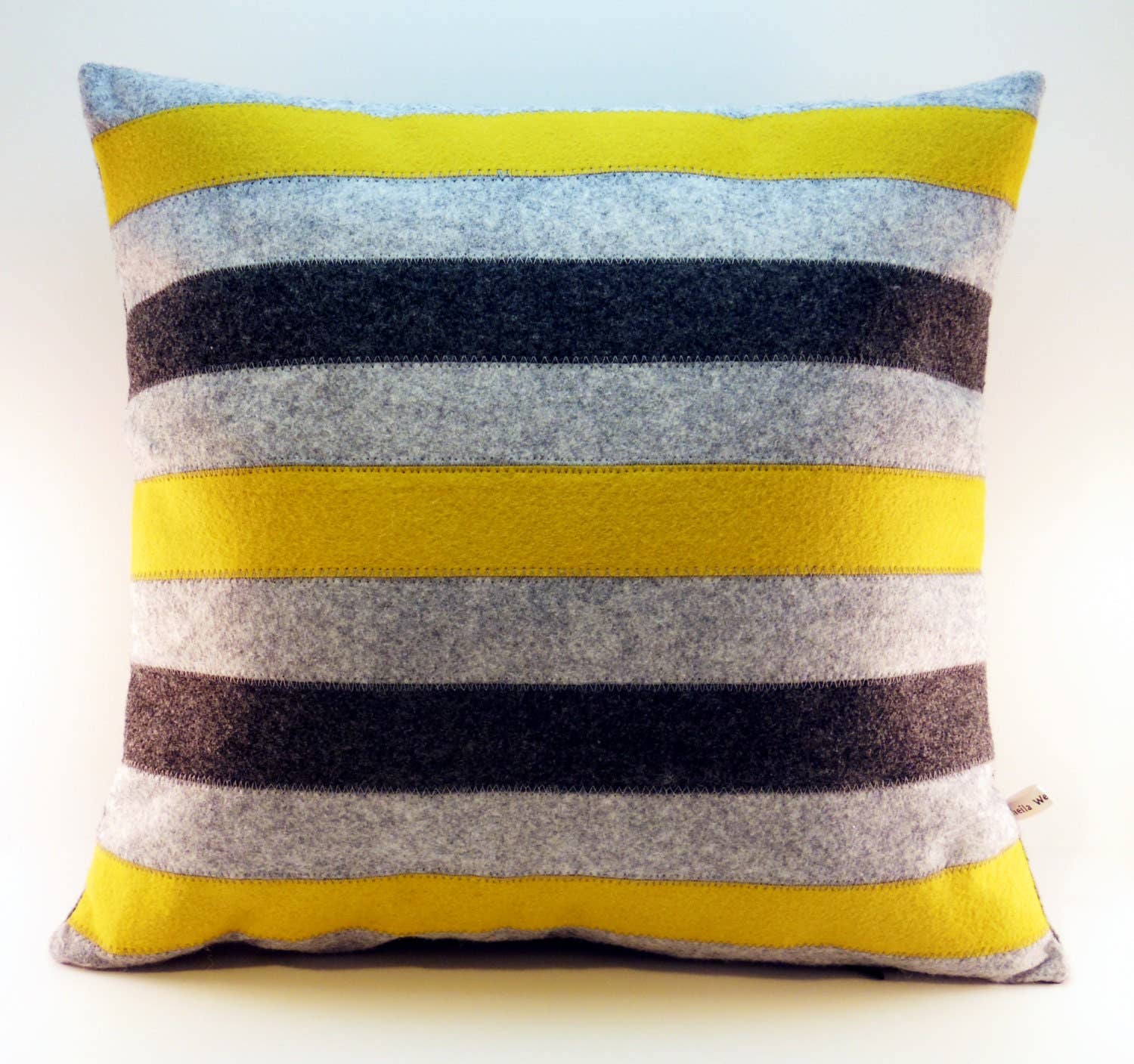 Square wool felt pillow featuring horizontal yellow, gray, black, and white stripes for home decor.