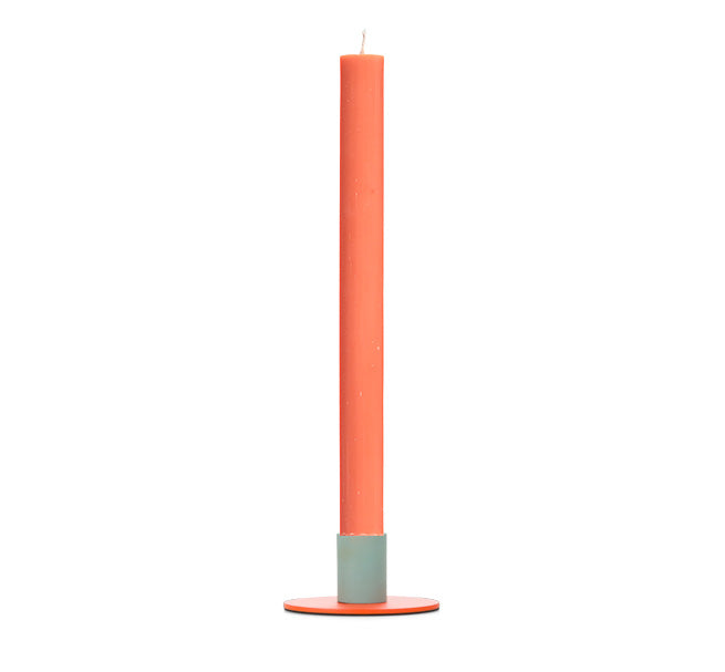 Tall orange tapered candle in a simple modern metal two-tone holder on a white background