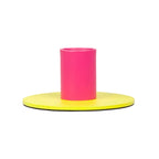 Small metal candle holder with bright pink cylindrical center and flat yellow base in a modern style