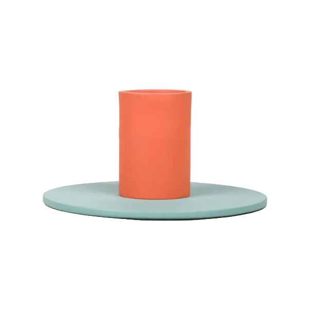 Minimalist two-tone metal candle holder with orange cylindrical holder and flat pale green base for home decor.