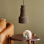 Small pendant light made from cork with a modern design hanging above a wooden side table and leather sofa