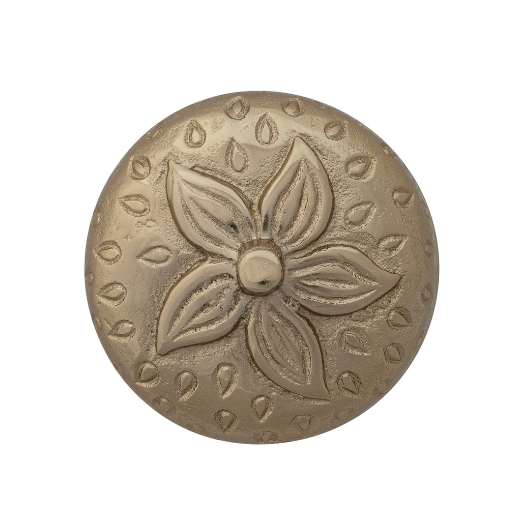 Decorative metal button with floral design on a white background
