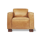 Tan leather armchair with wide cushioned arms and wooden block legs, modern furniture design.