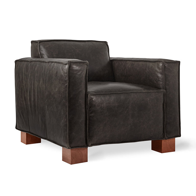 Black leather armchair with wide arms and wooden block legs, featuring a modern and sturdy design.