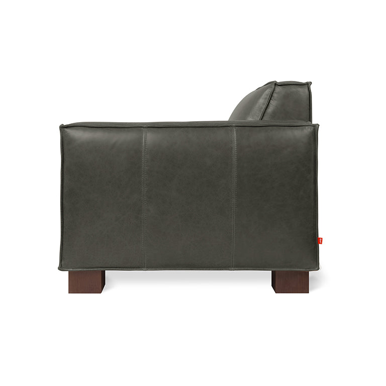 Side view of a dark gray leather chair with wooden block legs and clean, modern design