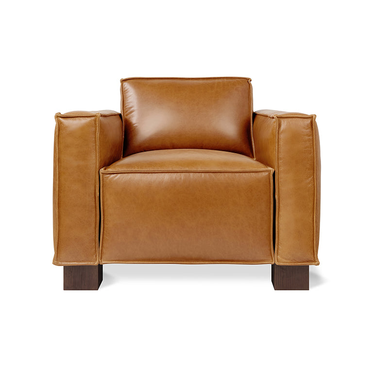 Modern leather armchair in warm tan with wide padded arms and dark wooden legs against white background