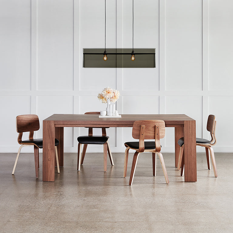 Modern dining room with wooden table and four mid-century dining chairs with walnut finish and black seats
