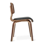Side view of a wooden dining chair with curved legs and a padded black seat and backrest.