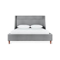 Modern gray upholstered bed with angled headboard and wooden legs, styled with white bedding and pillows