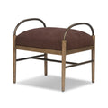 Brown fabric cushioned accent stool with wooden legs and curved metal armrests in a modern design