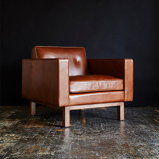 Brown leather armchair on a dark floor with a black background