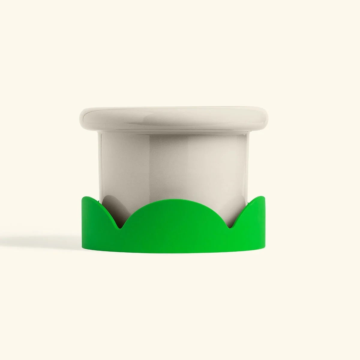 Green silicone petal-shaped drip tray under a white ceramic pot for home decor or plants.