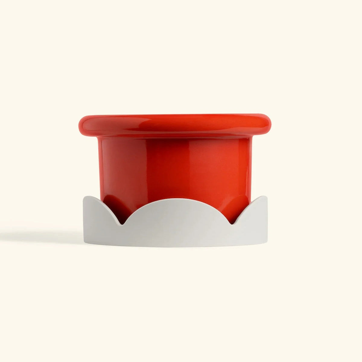 Red ceramic petal drip tray with beige base for home decor or plant protection on cream background