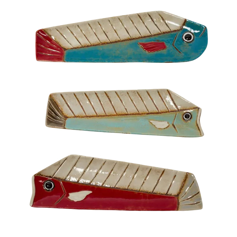 Three colorful ceramic fish-shaped dishes in red, blue, and beige with textured detailing and glazed finish.