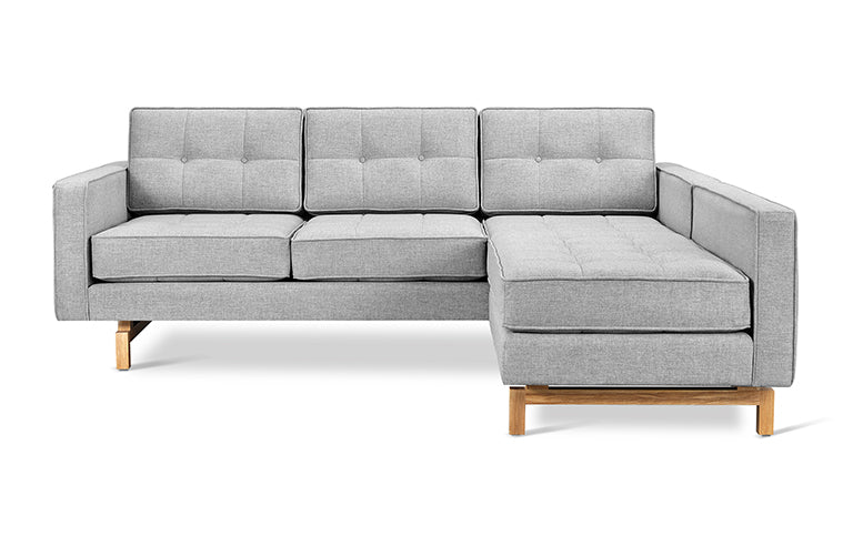 Light gray fabric bi-sectional sofa with tufted cushions and wooden legs in a modern minimalist style