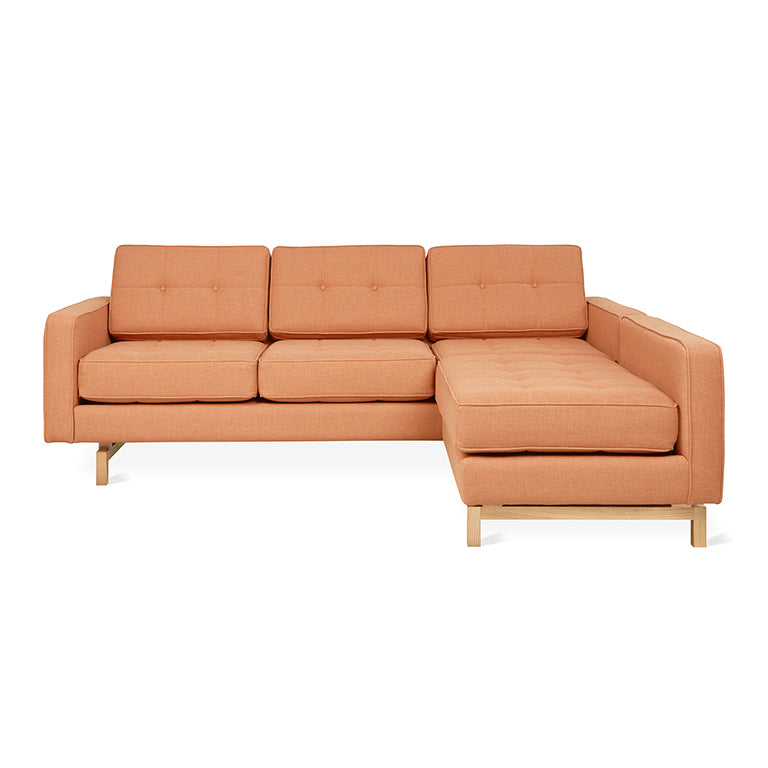 Orange fabric sectional sofa with button-tufted cushions and wooden legs, modern midcentury style lounge furniture