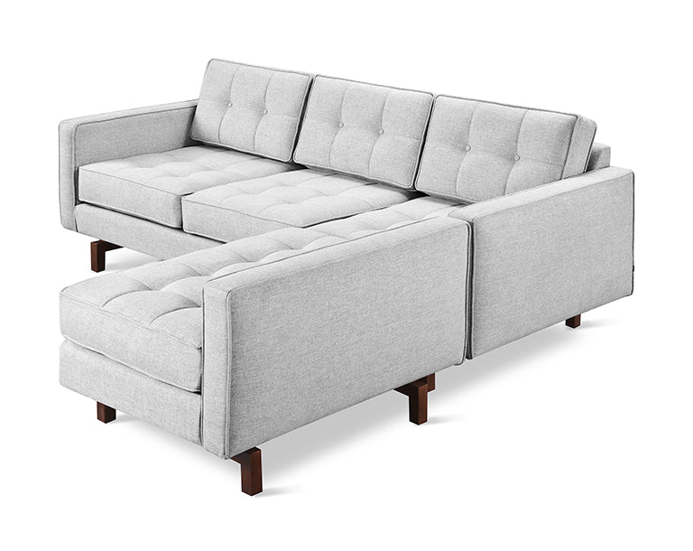 Light gray bi-sectional sofa with tufted cushions and wooden legs in a modern minimalist living room style