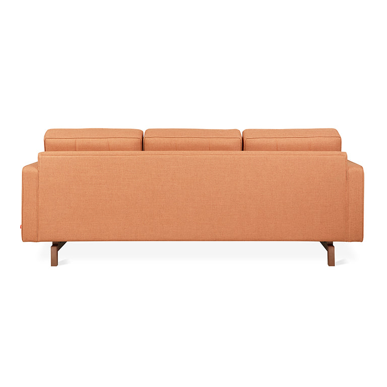 Back view of a modern orange fabric sectional sofa with wooden legs on a white background