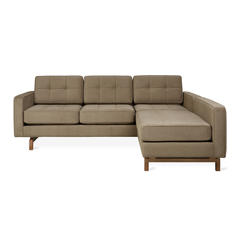 Modern beige fabric bi-sectional sofa with wooden legs, featuring tufted cushions and a chaise lounge on the right side.