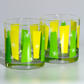 Two clear rocks glasses decorated with yellow and green geometric shapes and white star accents