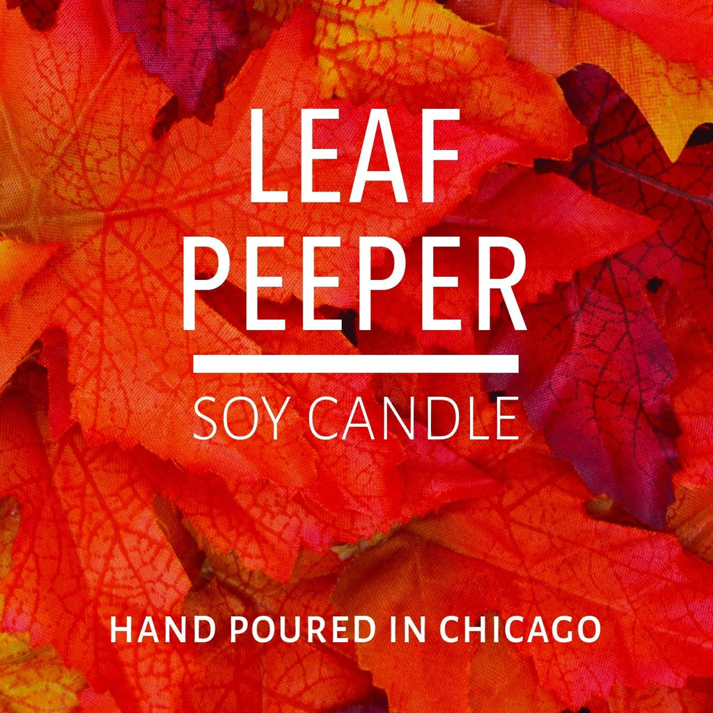 Close-up of vibrant orange and red autumn leaves with text about a soy candle hand poured in Chicago.