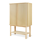 Tall wooden cabinet with vertical slatted doors and open lower shelf in light natural finish