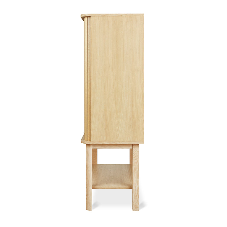 Side view of a tall wooden cabinet in light oak finish with legs and an open lower shelf for storage.