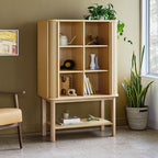 Light wood tall cabinet with open shelving and decorative items in a stylish modern living room setting