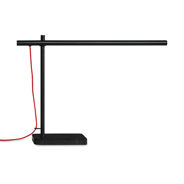 Modern black task lamp with a horizontal tubular design and a contrasting red power cord on a rectangular base