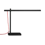 Modern black task lamp with a horizontal tubular design and a contrasting red power cord on a rectangular base