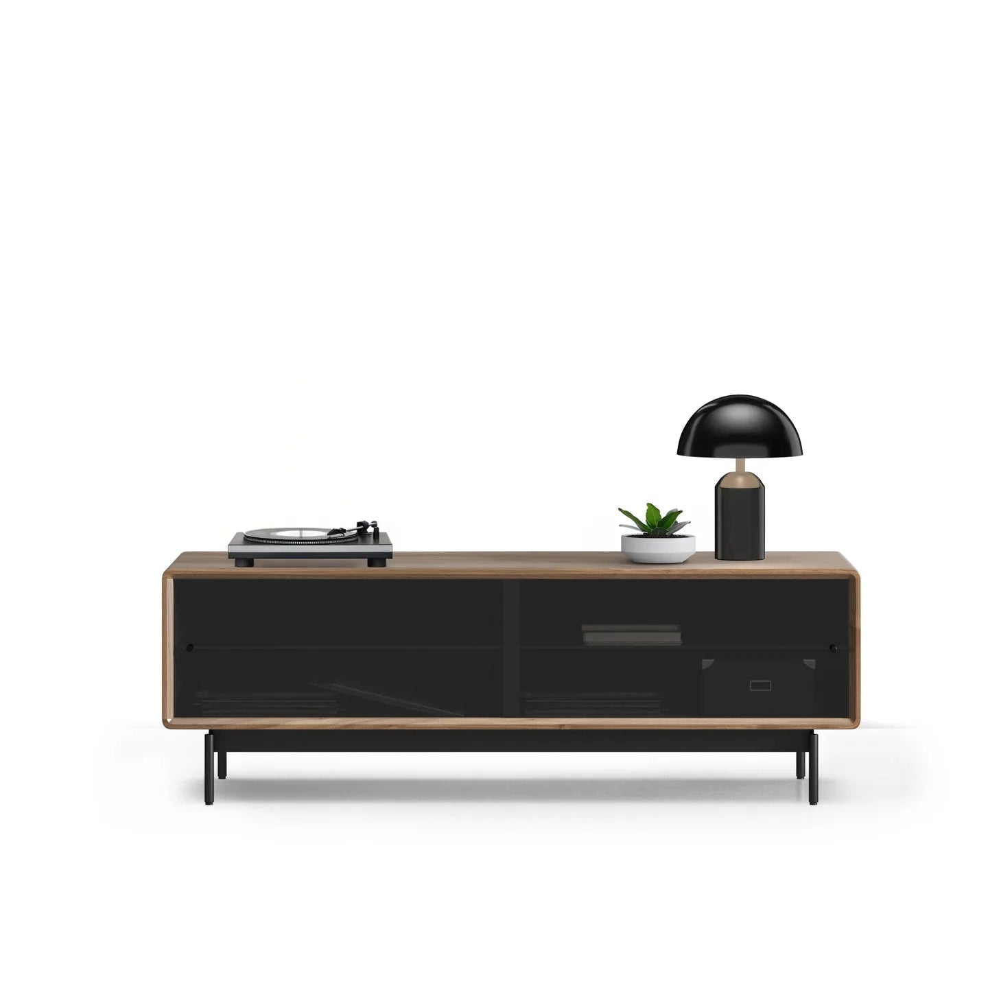Low wooden media console with black glass doors, holding a black dome lamp, small plant, and record player.