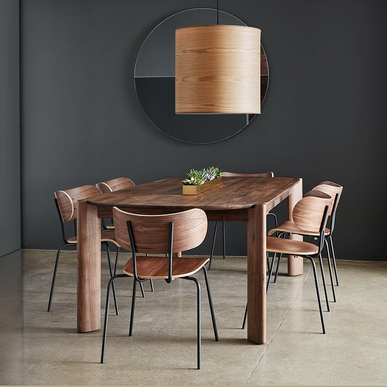 Large wooden pendant light hanging above a modern dining table with six wooden chairs in a minimalist room