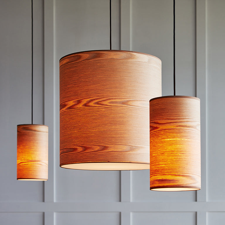 Three hanging pendant lights with warm ash wood veneer shades illuminating a modern interior space