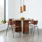 Two wooden Milton Small Pendant Lights hanging above a round wooden dining table with four modern chairs.