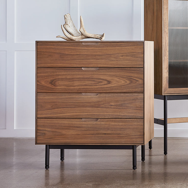 Midcentury modern walnut dresser with four drawers and black metal legs in a minimalist interior setting