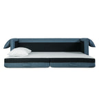 Modern blue fabric sofabed with black cushioned base and white pillow on a minimalist white background