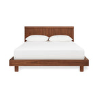 Midcentury modern walnut wood bed frame with slatted headboard and white bedding, minimalistic design