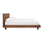 Modern wooden platform bed with walnut finish and simple white bedding against white background