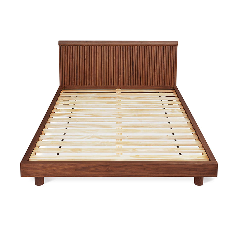 Walnut wooden bed frame with slatted base and vertically grooved headboard in midcentury modern style