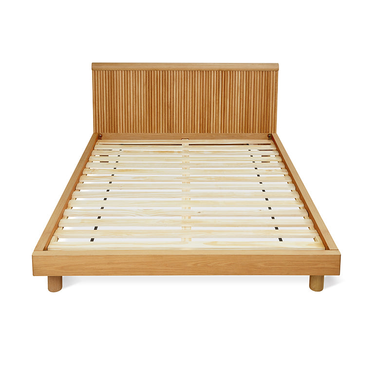 Wooden bed frame with slatted base and vertically grooved headboard in light oak finish