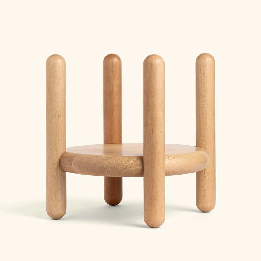 Round wood stand with four vertical rounded legs in natural beech finish on cream background