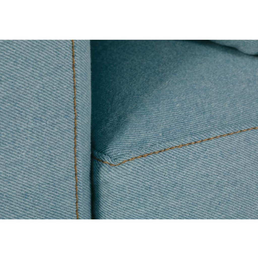 Close-up of blue denim upholstery with detailed stitching on a modern sofa cushion corner.
